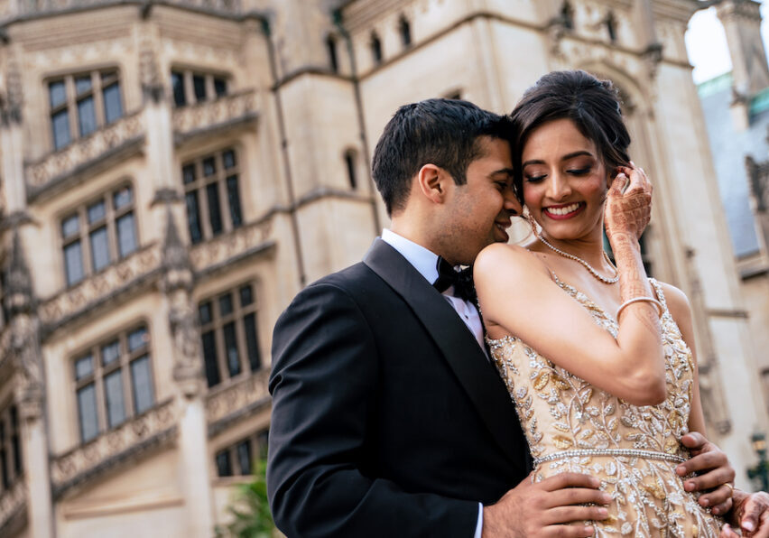Indian bride and groom embrace in front of Biltmore Estate