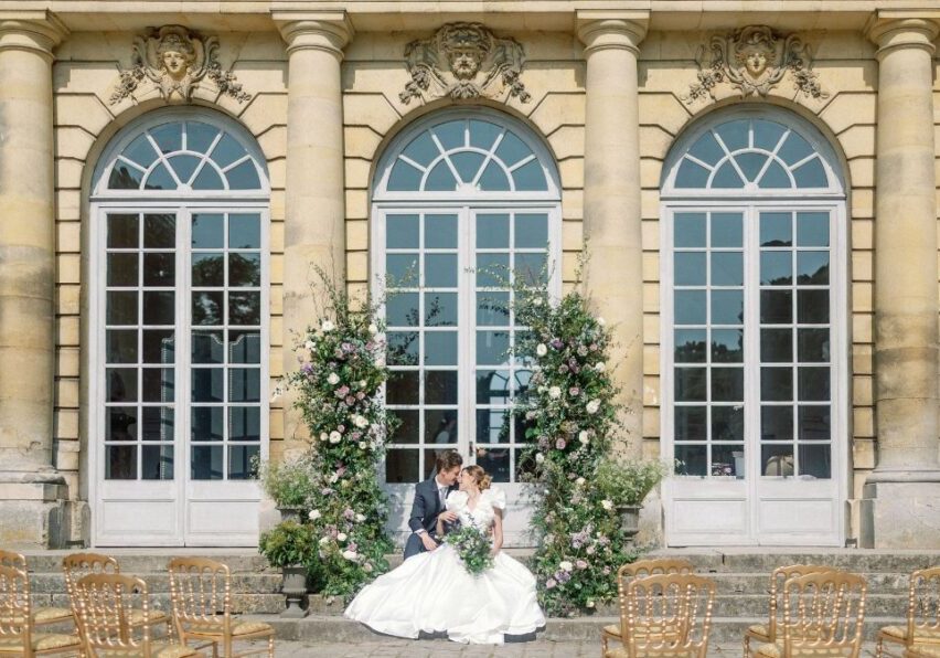 Wedding couple sit at altar in front of Chateau de Champlatreux