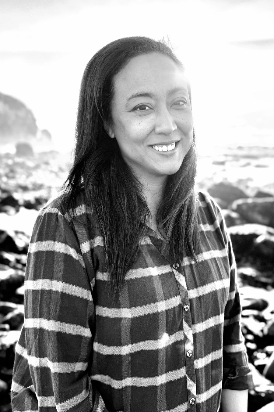 Marisol Acosta Headshot woman with dark hair smiling on rocky beach